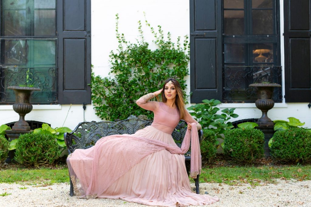 une femme portant une long robe pastel, assise sur un ban de jardin