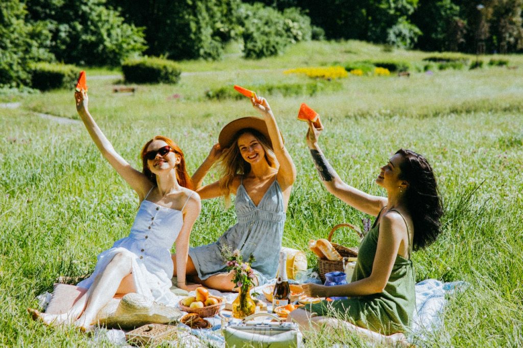 un groupe de jeunne femmes qui portent des Robes Guinguette Champêtre : Tendances Incontournables De La Mode Estivale, et qui sont assise en plein air