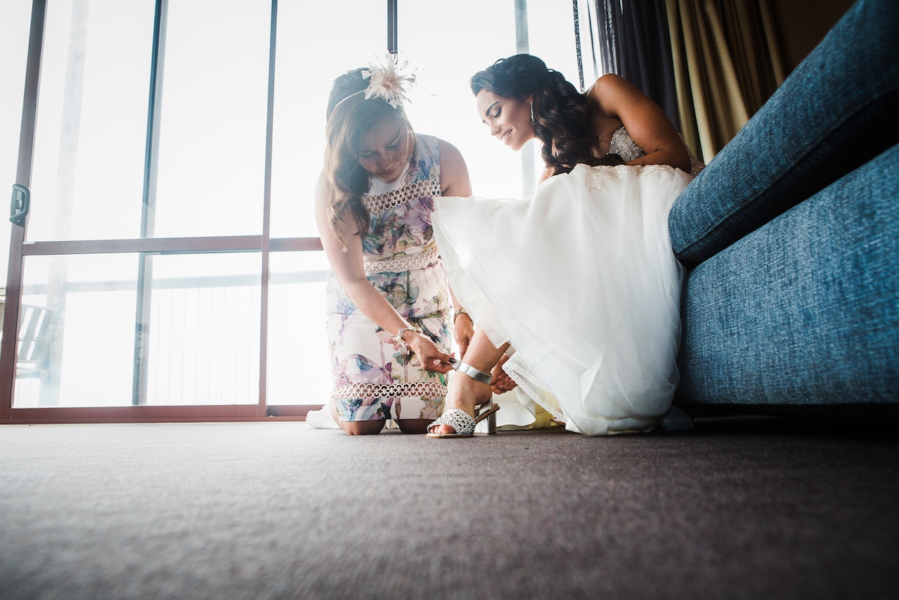 une femme qui aide sa copie a porter des accessoires pour sublimer sa robe de mariage