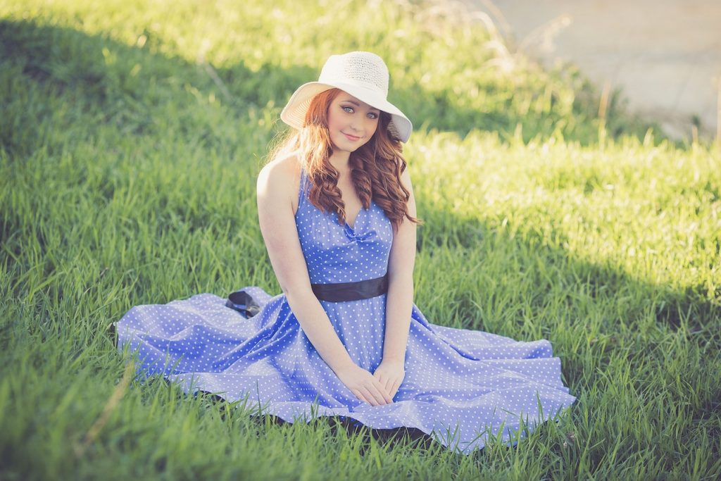 une femme qui porte une robe champetre bleu, assise sur le sol en plein air