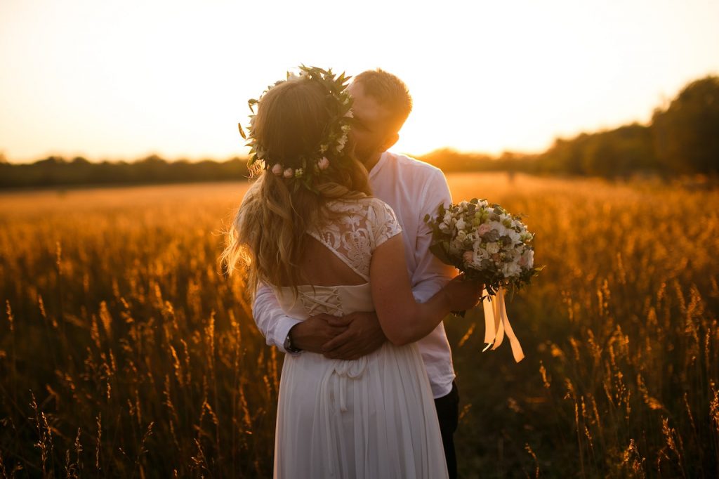 un couple de nouveau mariéé qui sembrasse au milieu d'un champ